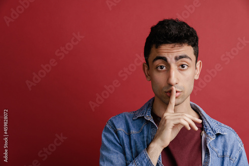 Young middle eastern man showing silence gesture at camera