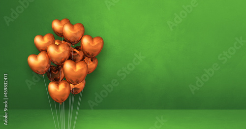 Copper heart shape balloons bunch on a green wall background. Horizontal banner.