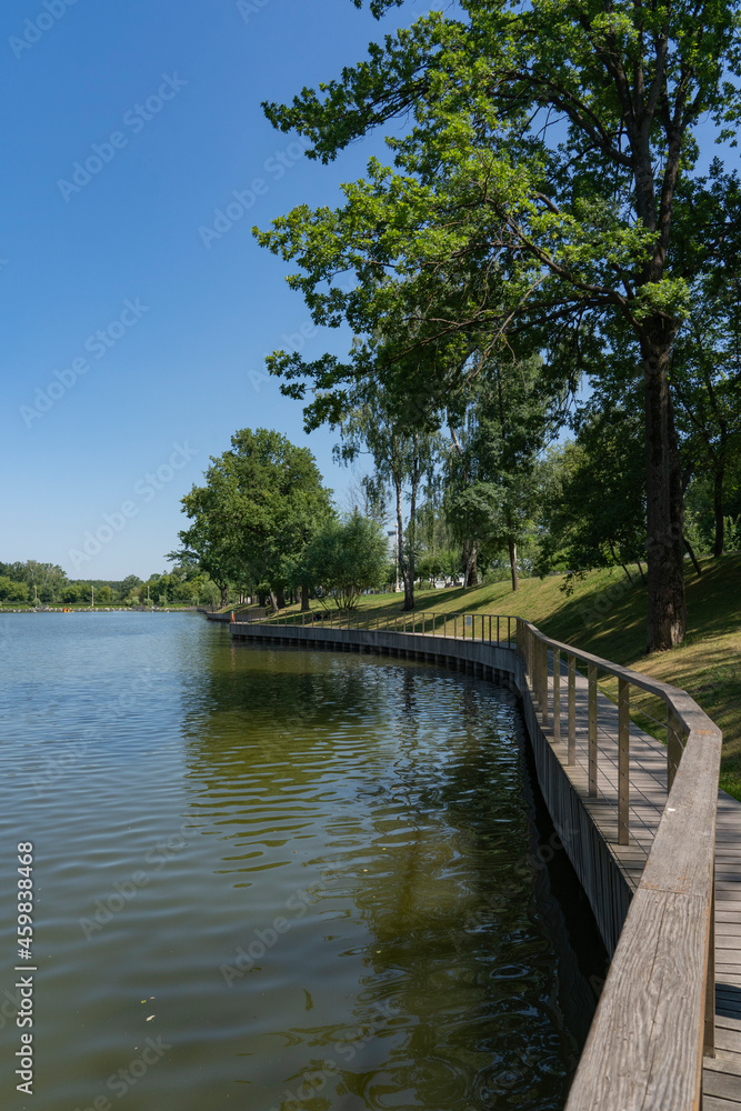 City pond embankment with railings in summer. City pond embankment with railings in summer.