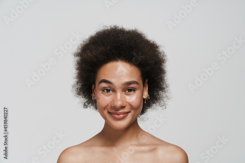 Black curly shirtless woman smiling and looking at camera