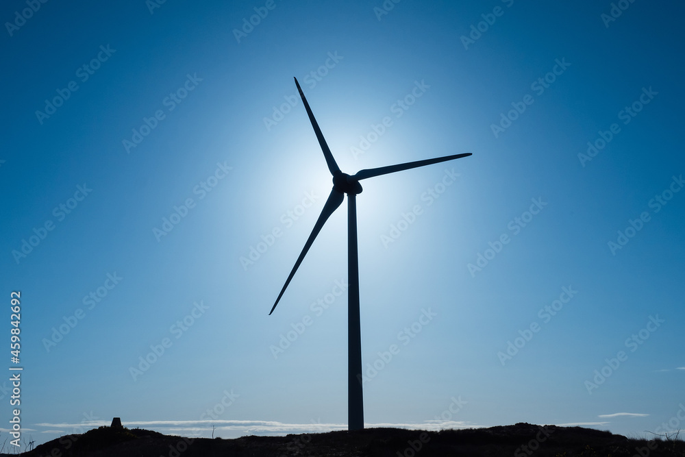 Silhouette of a wind electricity generator against clean blue sky. Warm sunny day. Copy space. Renewable green energy concept. Silhouette of a wind electricity generator against clean blue sky. Warm sunny day. Copy space. Renewable green energy concept.