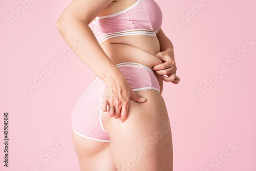 Overweight woman with fat hips and buttocks, obesity female body on pink background