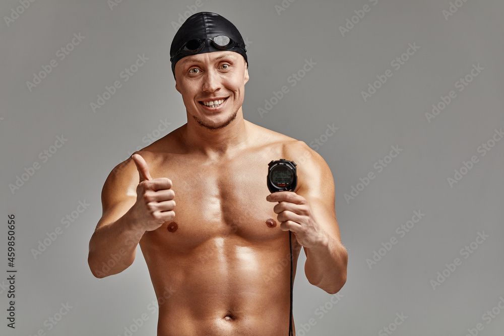 Excited swimer with stopwatch standing on gray background. New record. Motivation, advertising banner, place for text