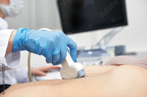 Female doctor gives the patient a female abdominal ultrasound. Ultrasound scanner in the hands of a doctor. photo