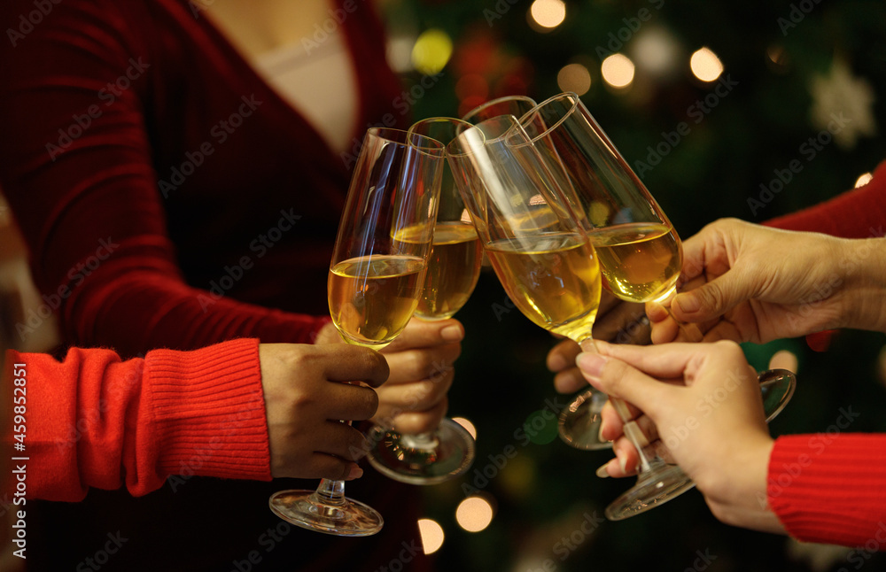 Beverage glasses clinking moment by cheerful woman friends on sweater as enjoy celebrating happy relationship at delightful event of Chirstmas night party