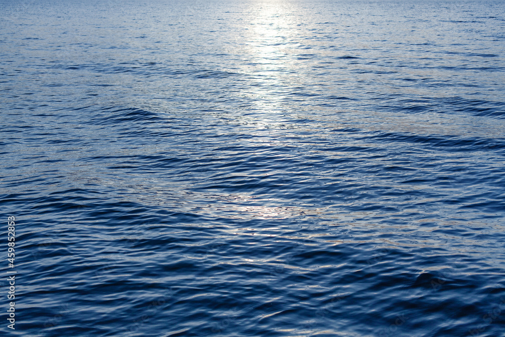 Naklejka premium Blue sea waves surface, ripple water texture, beautiful quiet ocean background, abstract aqua pattern backdrop, sunset reflection, sun light glow, dark night shiny moonlight at lake, river, top view