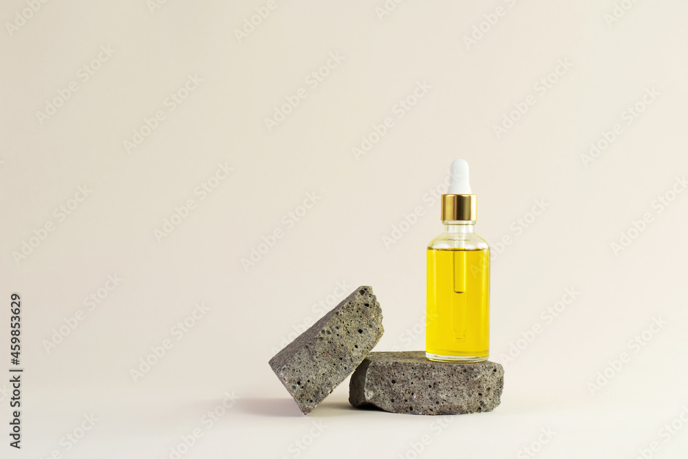 oil cosmetic bottle on a stone podium and wooden branch on beige background. Bottle of essential oil on the natural background. eco friendly care organic product. Spa concept. copy space oil cosmetic bottle on a stone podium and wooden branch on beige background. Bottle of essential oil on the natural background. eco friendly care organic product. Spa concept. copy space