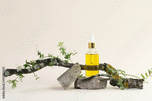 oil cosmetic bottle on a stone podium and wooden branch on beige background. Bottle of essential oil on the natural background. eco friendly care organic product. Spa concept. copy space