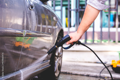 Human hand using black high-pressure hoses to clean the car. © Kanthita