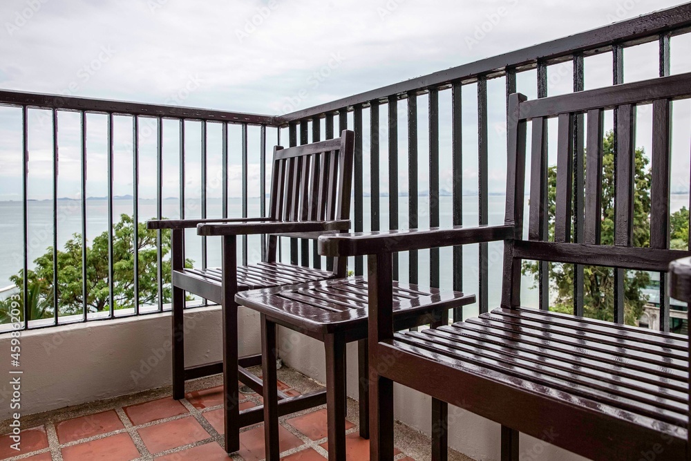 Empty brown wood chair and table set on balcony on high rise building with sea view Empty brown wood chair and table set on balcony on high rise building with sea view