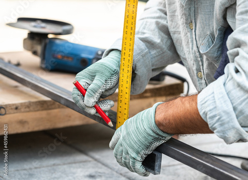 man measures metal with a ruler for cutting