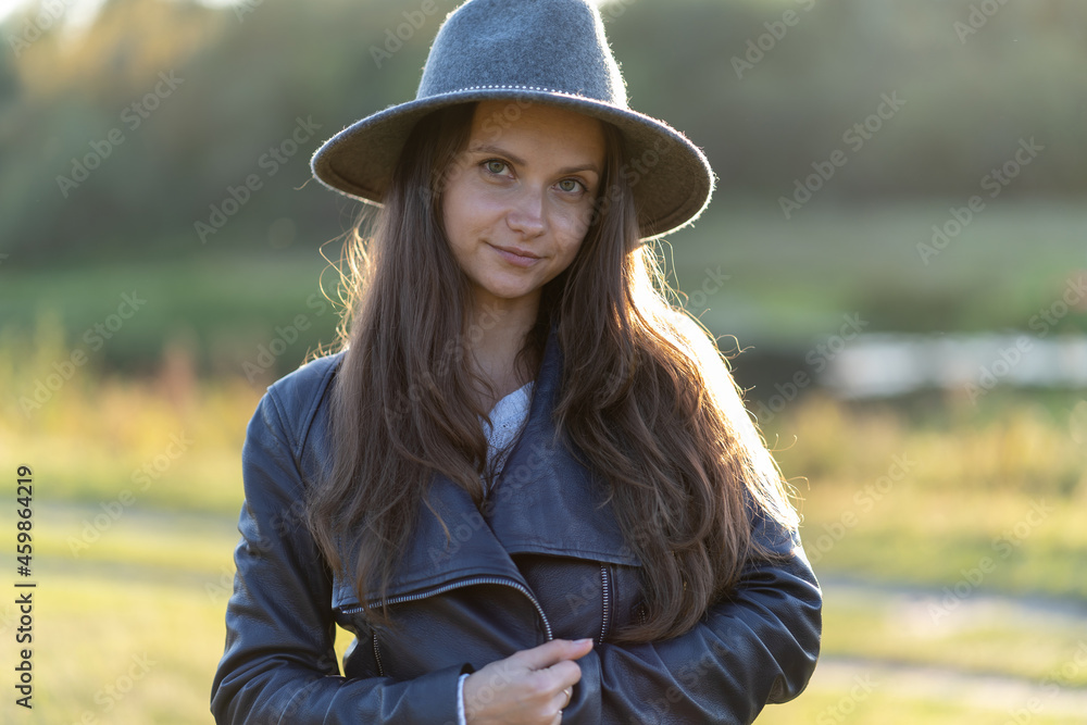 A woman in a hat smiles in the bright glow of sunset rays