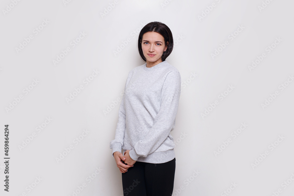 Cheerful young woman brunette in a light grey sweater, isolated on white background. Space for text. Cheerful young woman brunette in a light grey sweater, isolated on white background. Space for text.