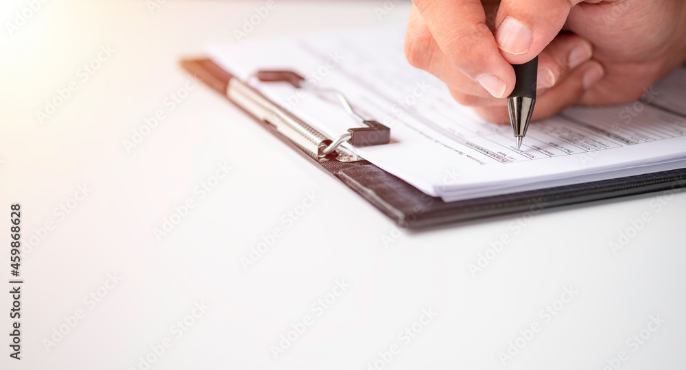 Hand using writing pen with questionnaire or paperwork survey
