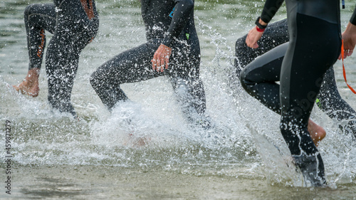 Cut out of people in a wetsuits running into a lake