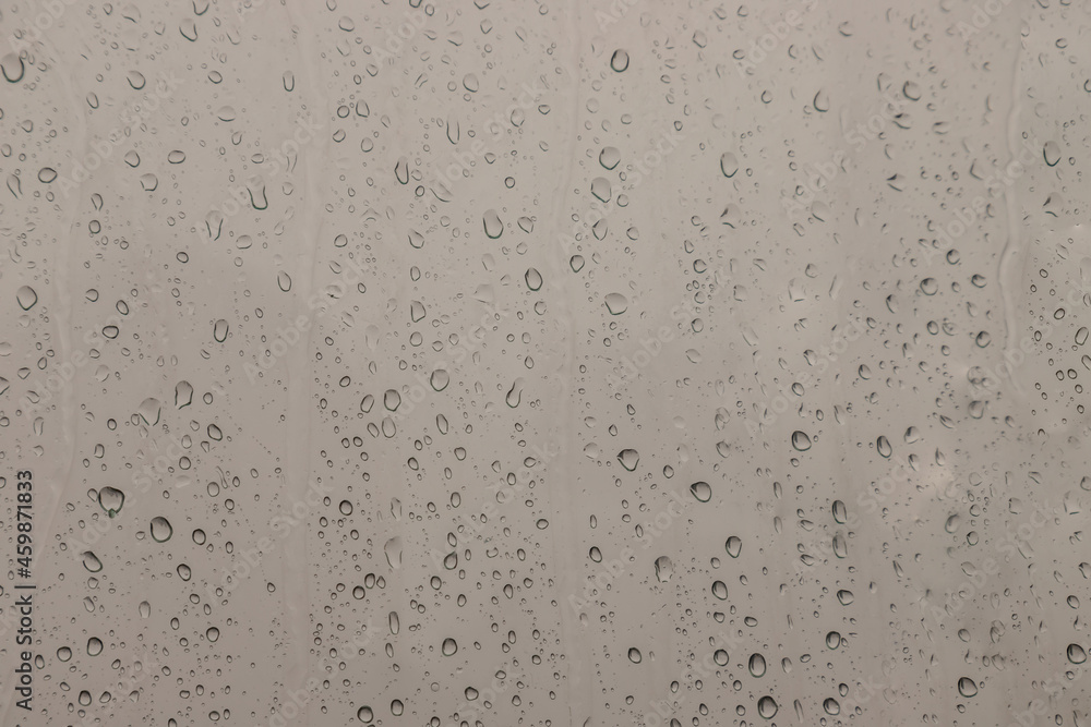 Water rain drops on window glass surface with cloudy background for your design. Natural Pattern of raindrops on glass background. Copy space, No focus, specifically.