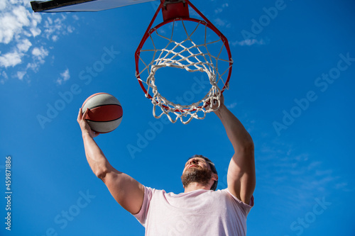 muscular man player throw basketball ball through basket, male basketball