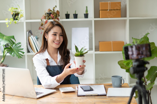 Young asian woman startup small business freelance sitting with parcel box and computer laptop on wood table in living room at home, Online marketing packing box delivery concept