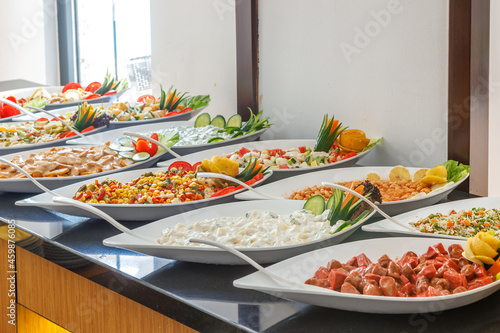 A row of large plates with various dishes. Buffet breakfast.