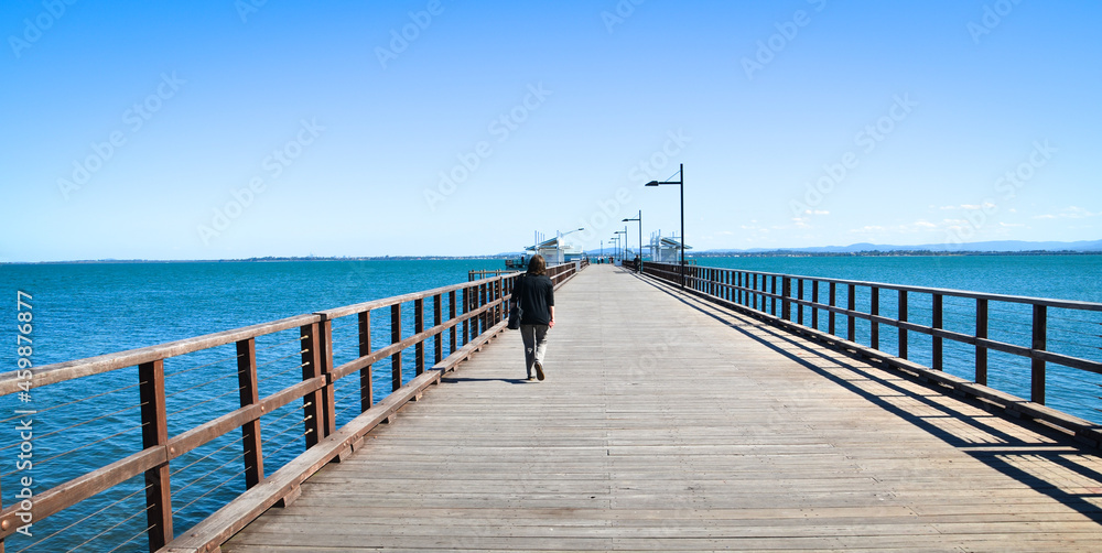 Women walking along a jetty with a bright blue sky