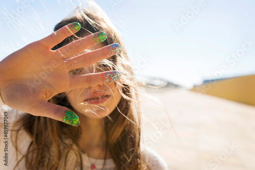 Woman covering face with multi-colored glitter on palm photo