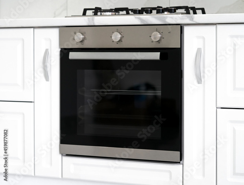 Gas stove with and embedded electric oven at brand new modern white kitchen