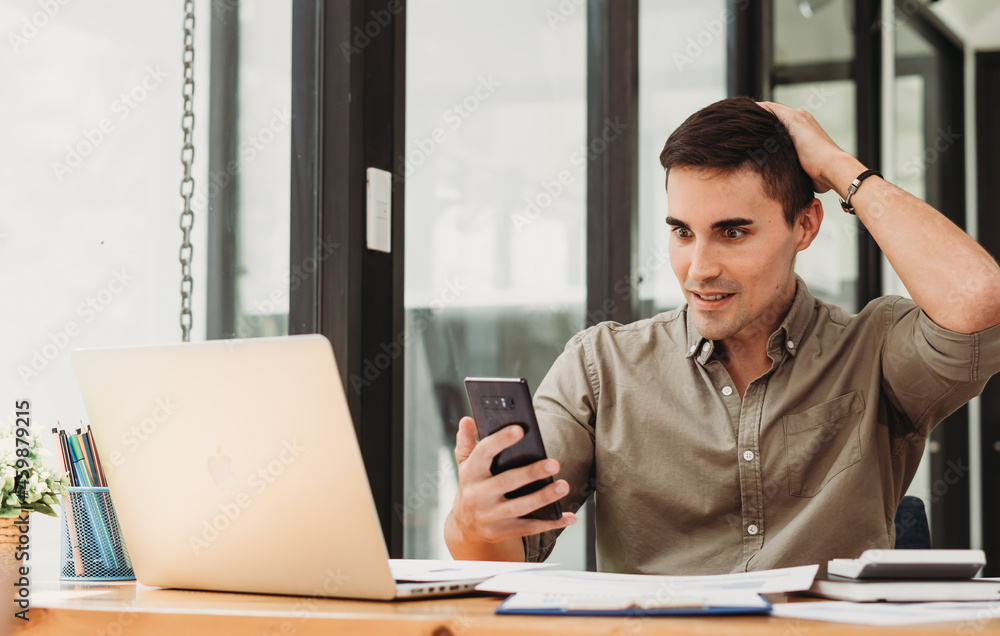 Handsome businessman in modern office looking on laptop Handsome businessman in modern office looking on laptop