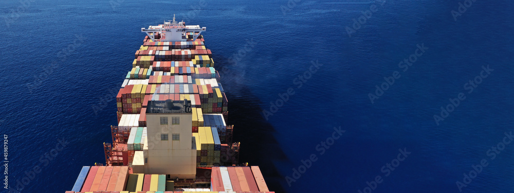 Aerial drone ultra wide panoramic view above huge colourful container carrier vessel cruising deep blue open ocean sea - obrazy, fototapety, plakaty 