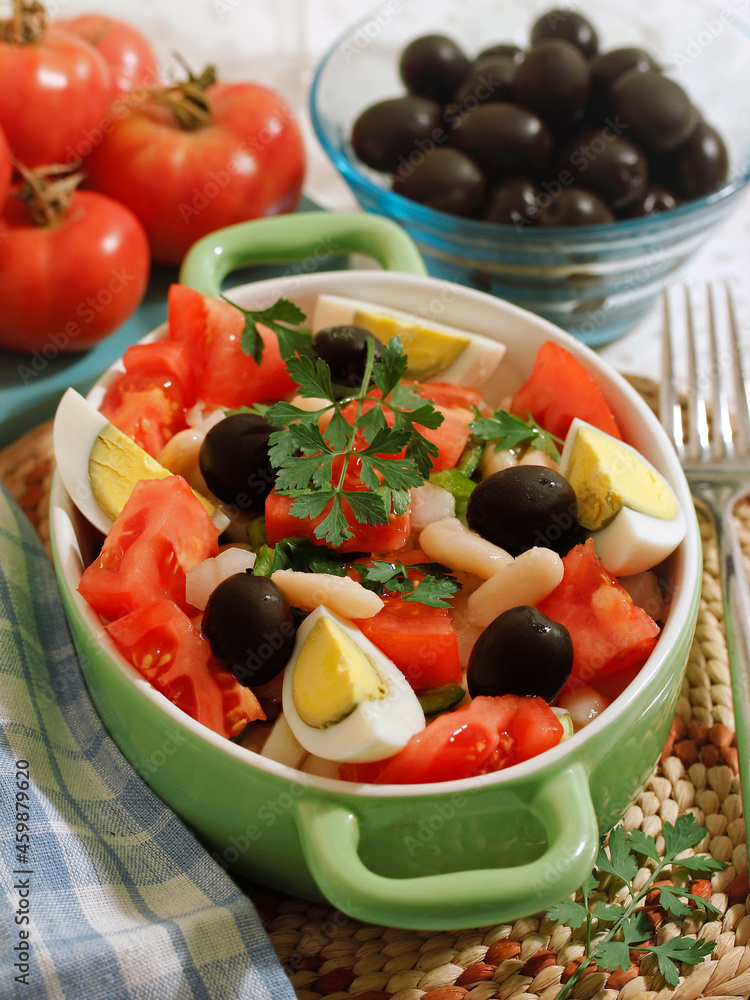 Salad with beans, olives, tomatoes, and eggs.