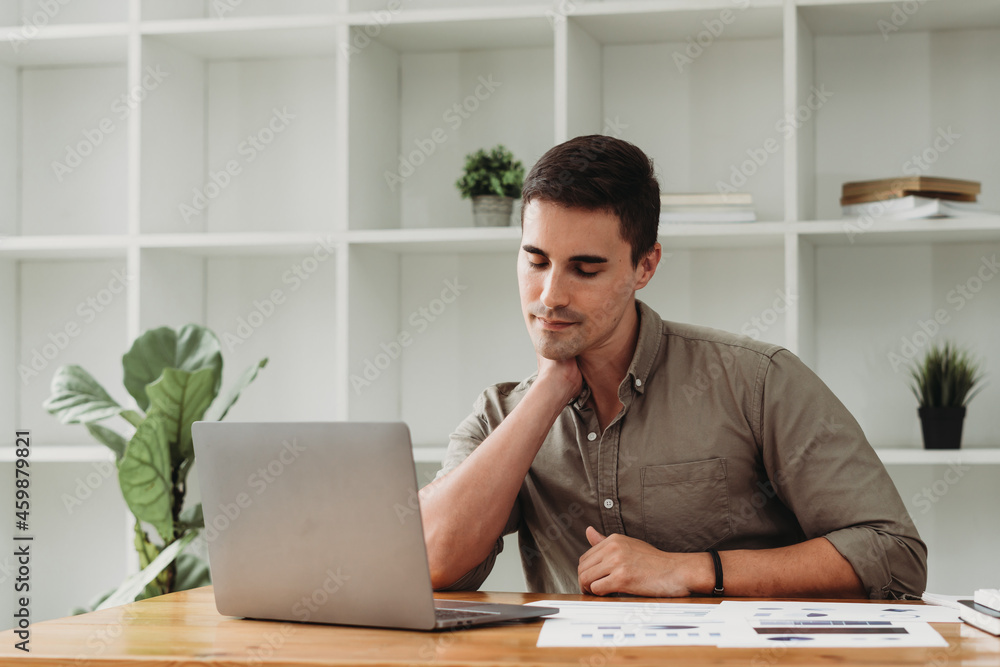 Fototapeta premium Feeling exhausted. Frustrated young handsome man looking exhausted while sitting at his working place.