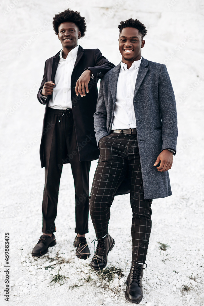 Two trendy African black men, against the backdrop of rocky mountains, in stylish classic clothes Two trendy African black men, against the backdrop of rocky mountains, in stylish classic clothes