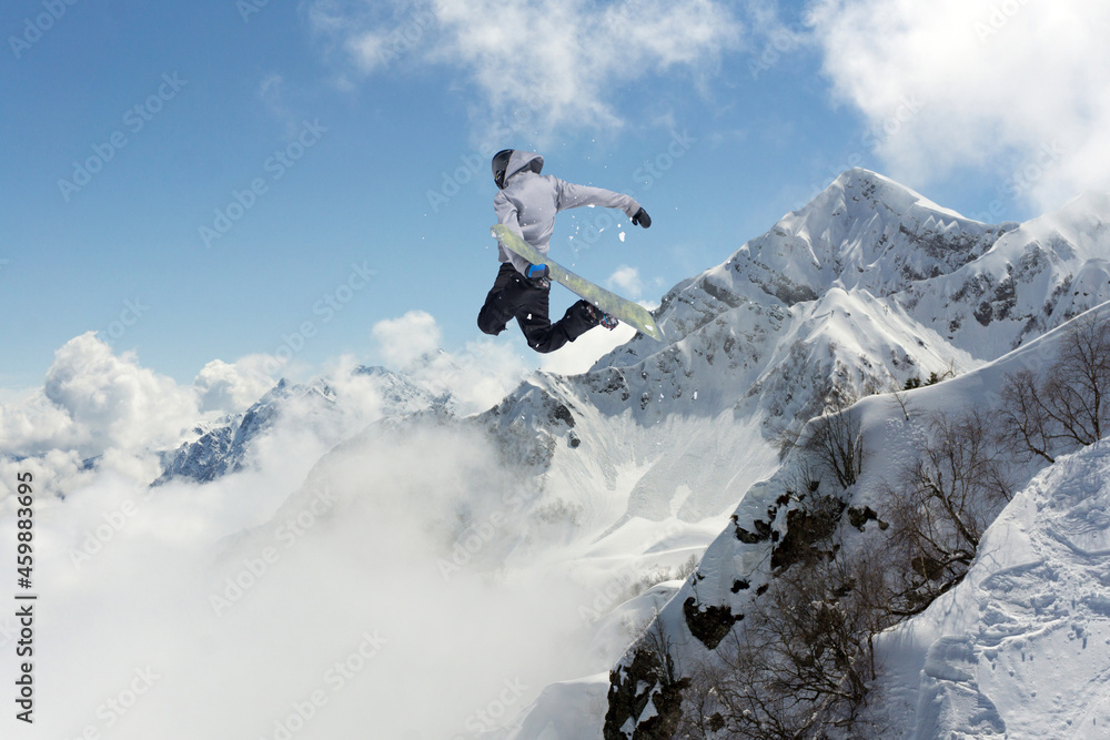 A jumping snowboarder in the mountains. Snowboarding, winter extreme sport. A jumping snowboarder in the mountains. Snowboarding, winter extreme sport.