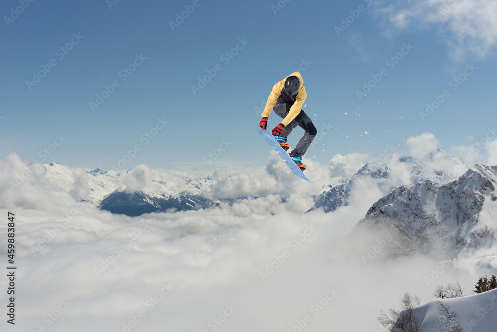 A jumping snowboarder in the mountains. Snowboarding, winter extreme sport.