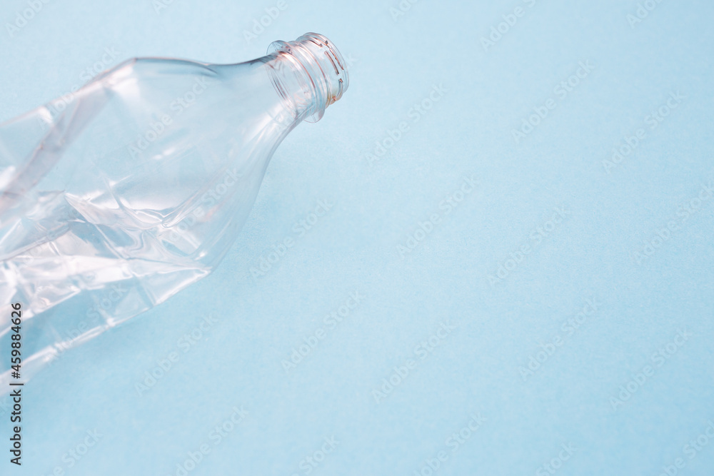 Empty crumpled plastic bottle on blue background with place for text. Copy space. Recycling concept. Ecology problems. Flat lay. Empty crumpled plastic bottle on blue background with place for text. Copy space. Recycling concept. Ecology problems. Flat lay.