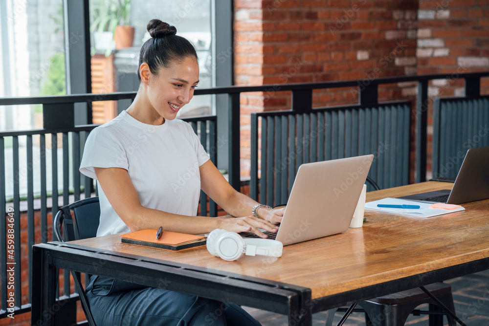 Smiling female professional using laptop while sitting t desk in office Smiling female professional using laptop while sitting t desk in office