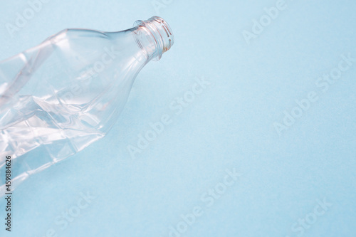 Empty crumpled plastic bottle on blue background with place for text. Copy space. Recycling concept. Ecology problems. Flat lay. © firax