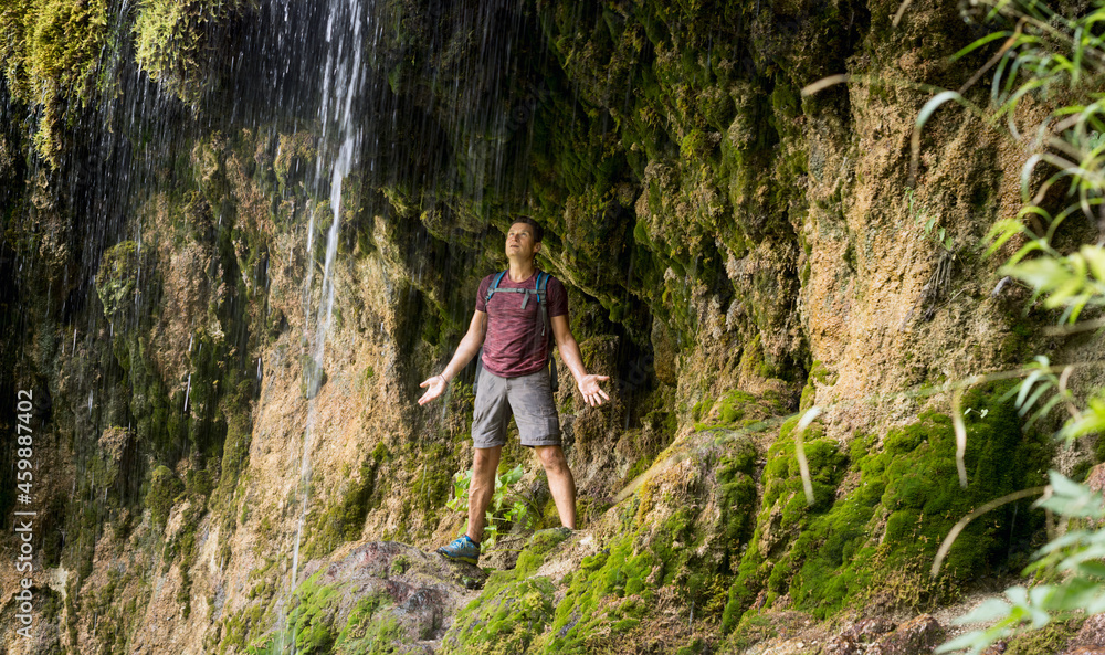 Mature man hiking under the rocky cliffs of Sipote waterfall, Transylvania region, Romania, Europe