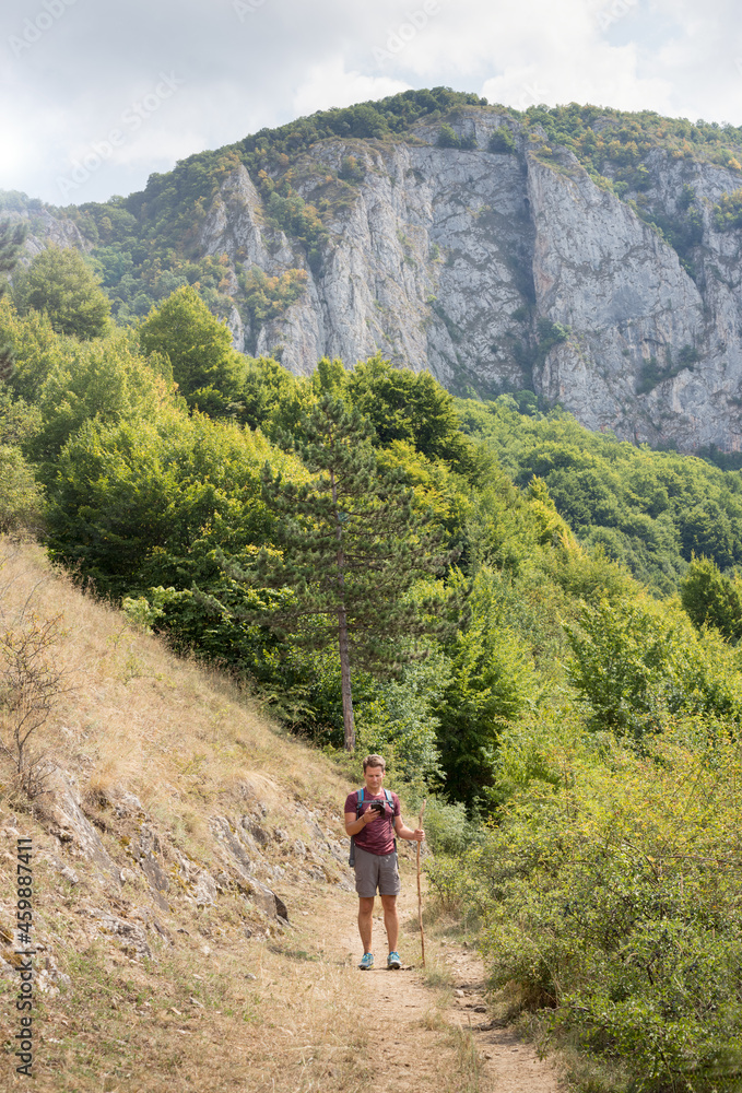 Adult man on a hike is guided by online maps, in the mountains in summer, Romania, Europe