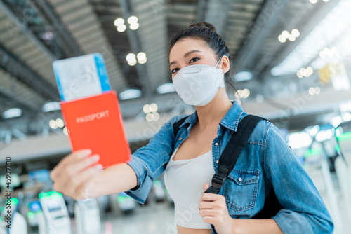 happiness smiling asian adult female wear face mask hand gesture showing passport and blank screen smartphone at aitport terminal,asian female ready to travel after lockdown ia over at airport