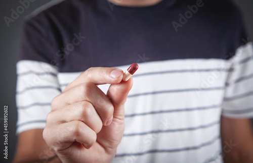 Close up of a man holding a capsule.