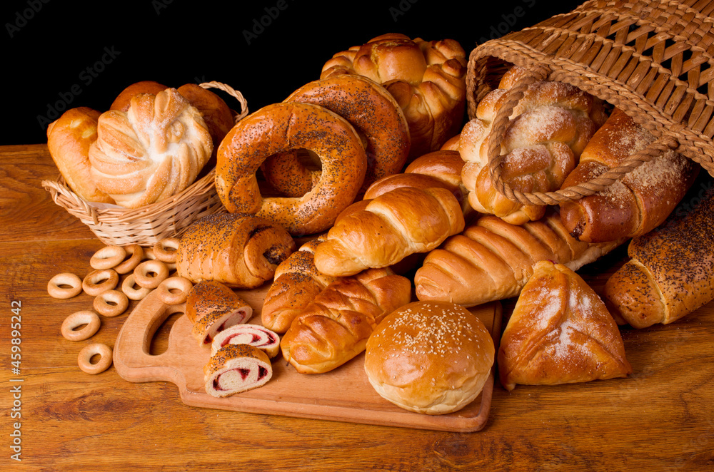 Baked bread rolls, pretzels, biscuits on a wooden table.