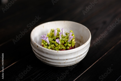 Red meat tartare decorated and plated with flowers and garden green