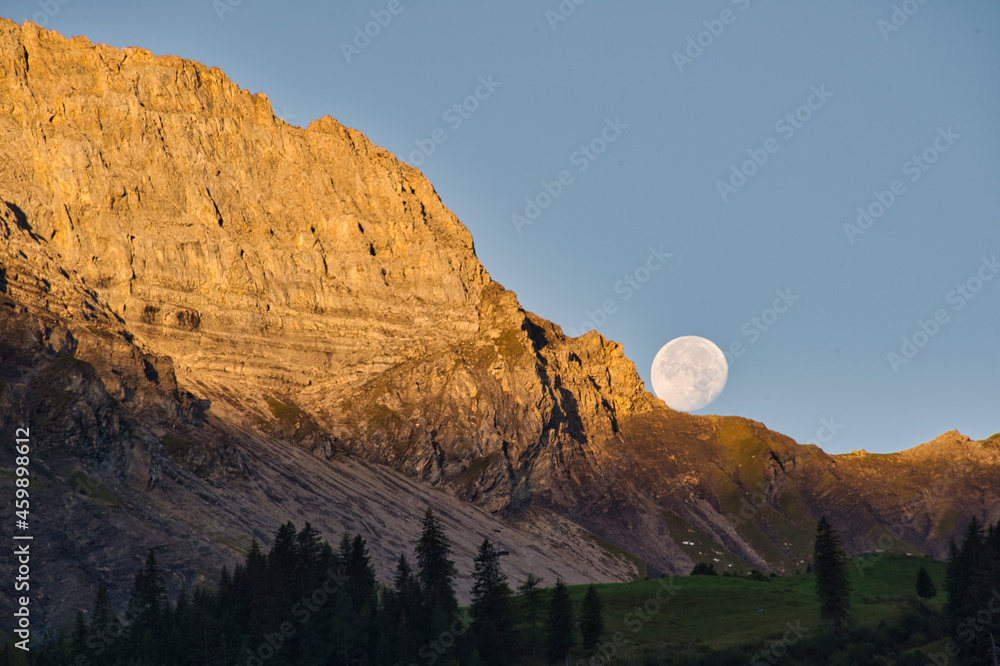 Setting moon in the Swiss mountains on a rock 