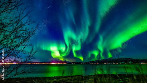Nordlichter in Troms, Norwegen. Aurora Borealis spiegelt sich im Fjord und leuchtet über den schneebedeckten Bergen. the lady dance in the sky, northern light