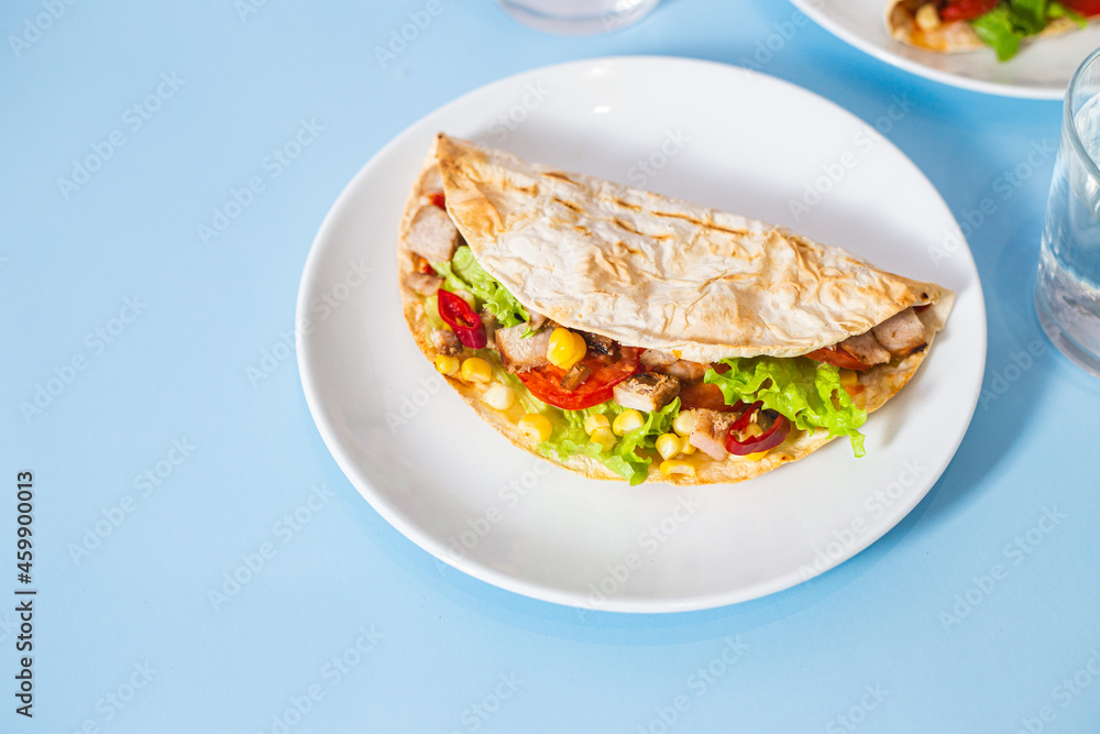 corn tortilla stuffed with meat and vegetables on a blue background. Taco corn tortilla stuffed with meat and vegetables on a blue background. Taco