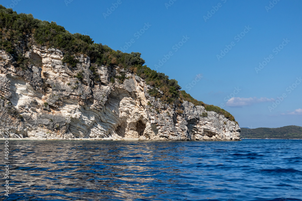 Fototapeta premium Blue reflective vivid water of Ionian Sea with rocky white cliffs and bright sky. Nature of Lefkada island in Greece. Summer vacation travel destination