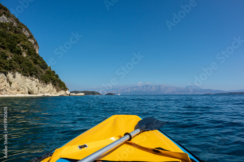 Yellow raft boat and paddle on blue clear calm Ionian Sea bay, view from boat. Nice clouds reflection and scenic rocky cliffs coast. Lefkada island in Greece. Idyllic travel activity © Kathrine Andi