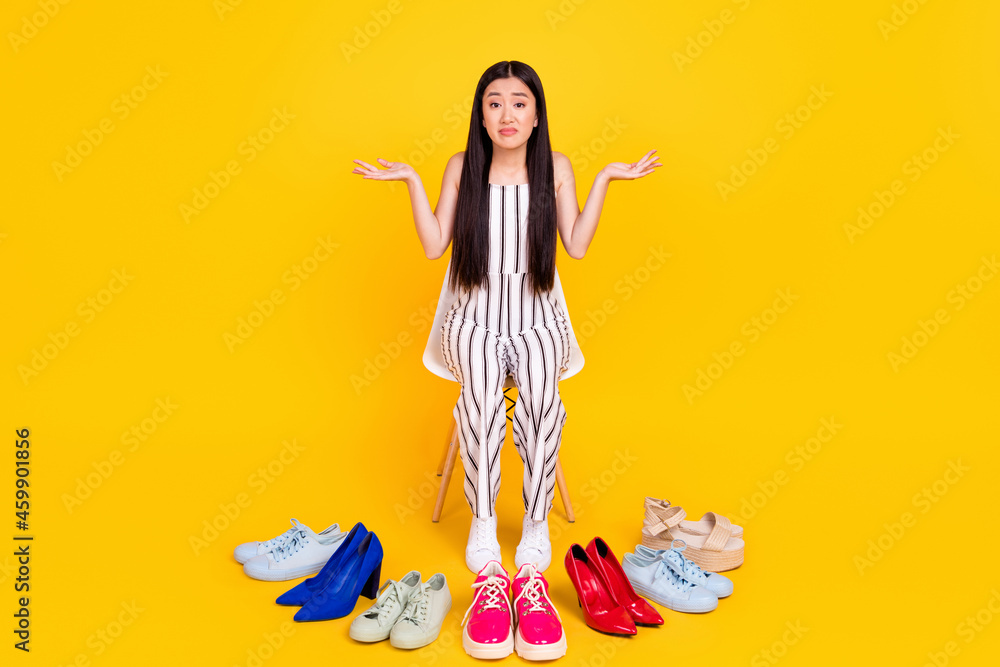 Obraz premium Full length body size photo girl cant choose footwear in shopping mall shrugging shoulders isolated vivid yellow color background