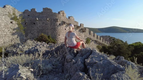 Woman waving a Croatian flag on Wall of Ostrica also called CHINESE WALL. Grebastica village in Sibenik-Knin County. Also called Bedem Grebastica historic defensive wall of Croatian-Ottoman wars. photo