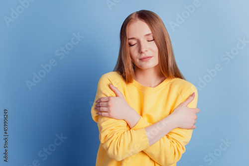 Portrait of serene inspired lady close eyes hands hug shoulders enjoy on blue background